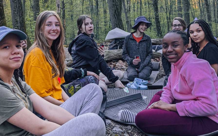 a group of girls sit at a campsite on a course with outward bound